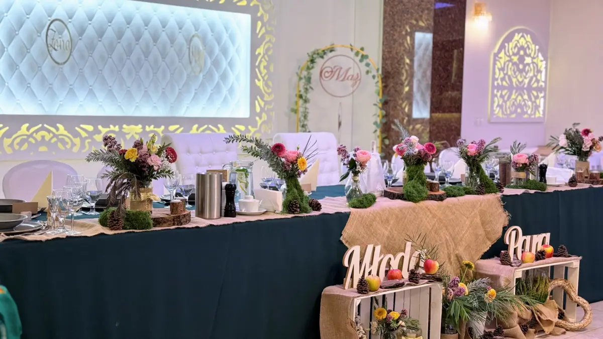 Stół pary młodej w butelkowej zieleni z drewnianym napisem Młoda Para i polnymi bukietami