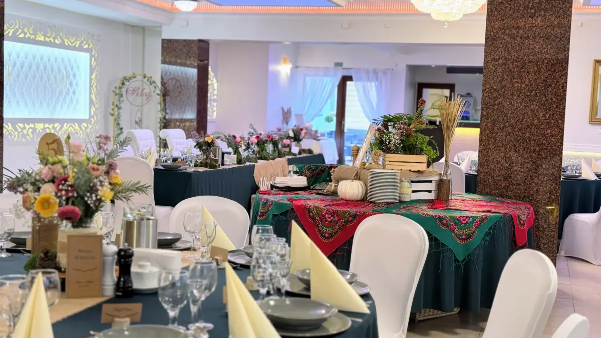 Sala weselna z góralską chustą na stole wiejskim i stosem talerzy