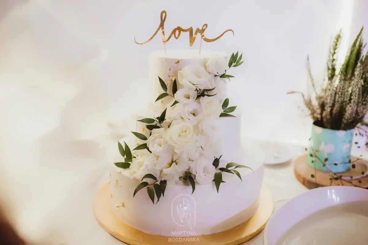 Trzypiętrowy biały tort weselny z żywymi różami i złotym napisem love