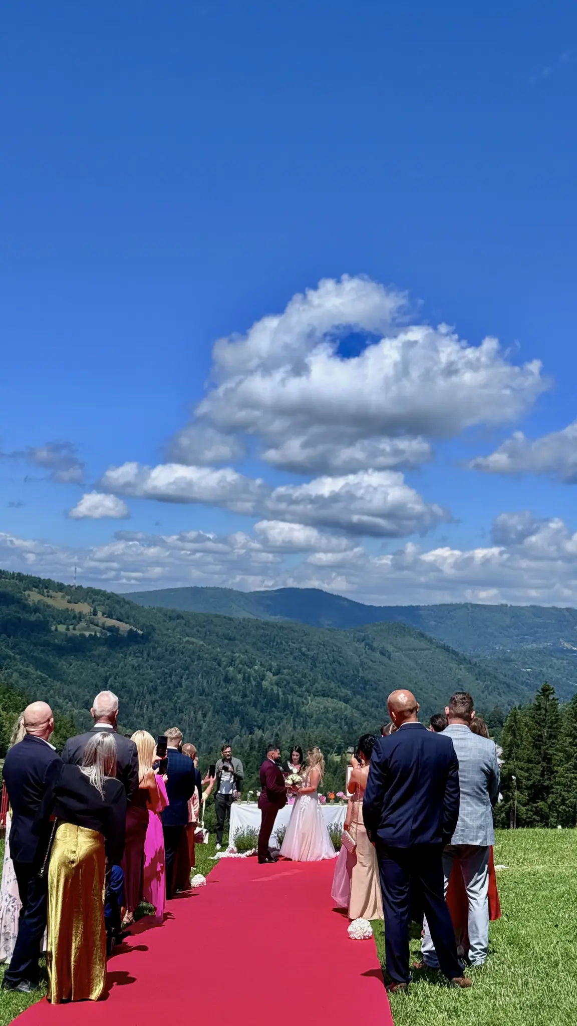Para młoda podczas ceremonii plenerowej przy stole, goście i panorama gór w tle