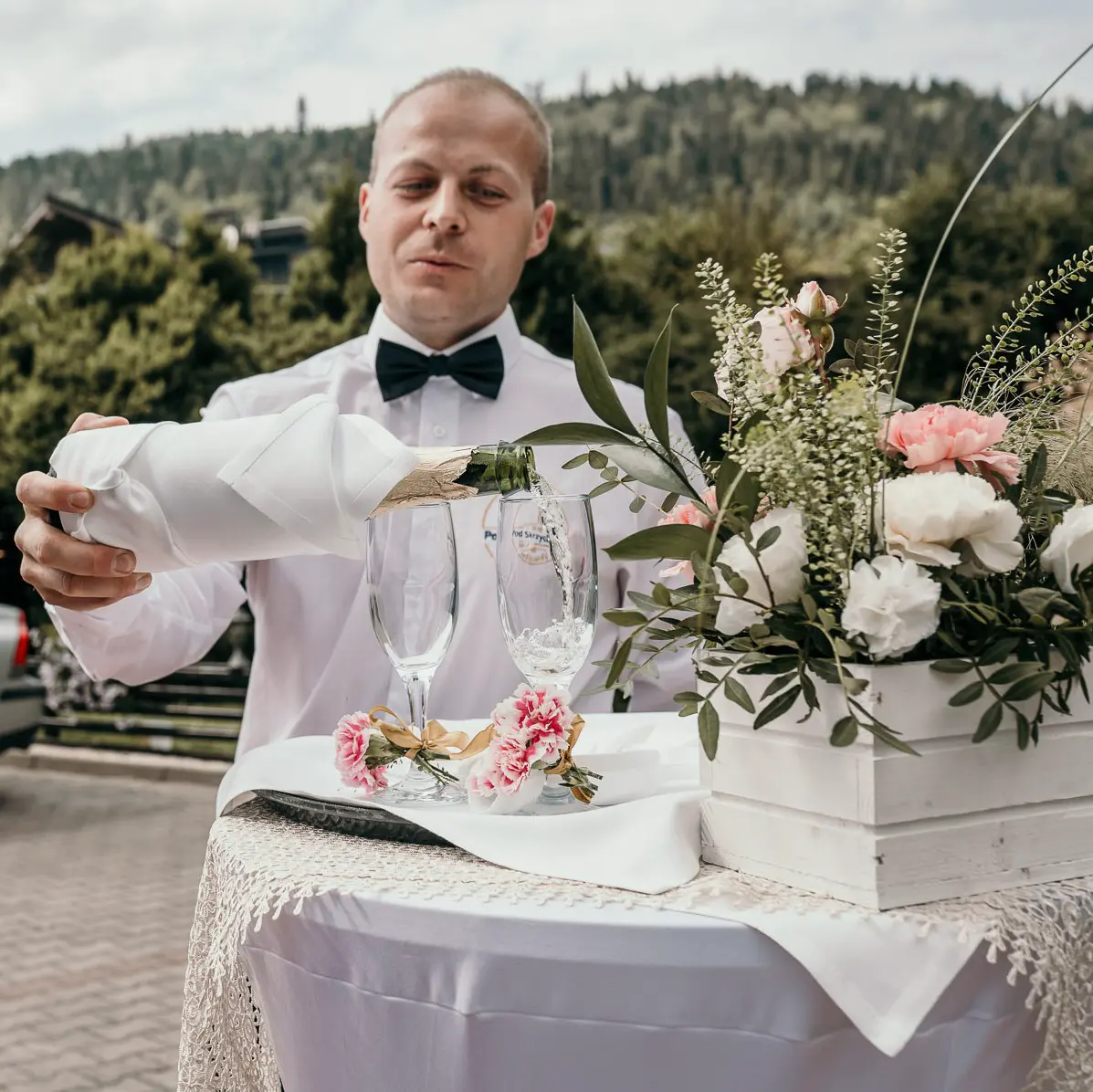 Kelner nalewa wino musujące do kieliszków na powitalny toast przed gościńcem